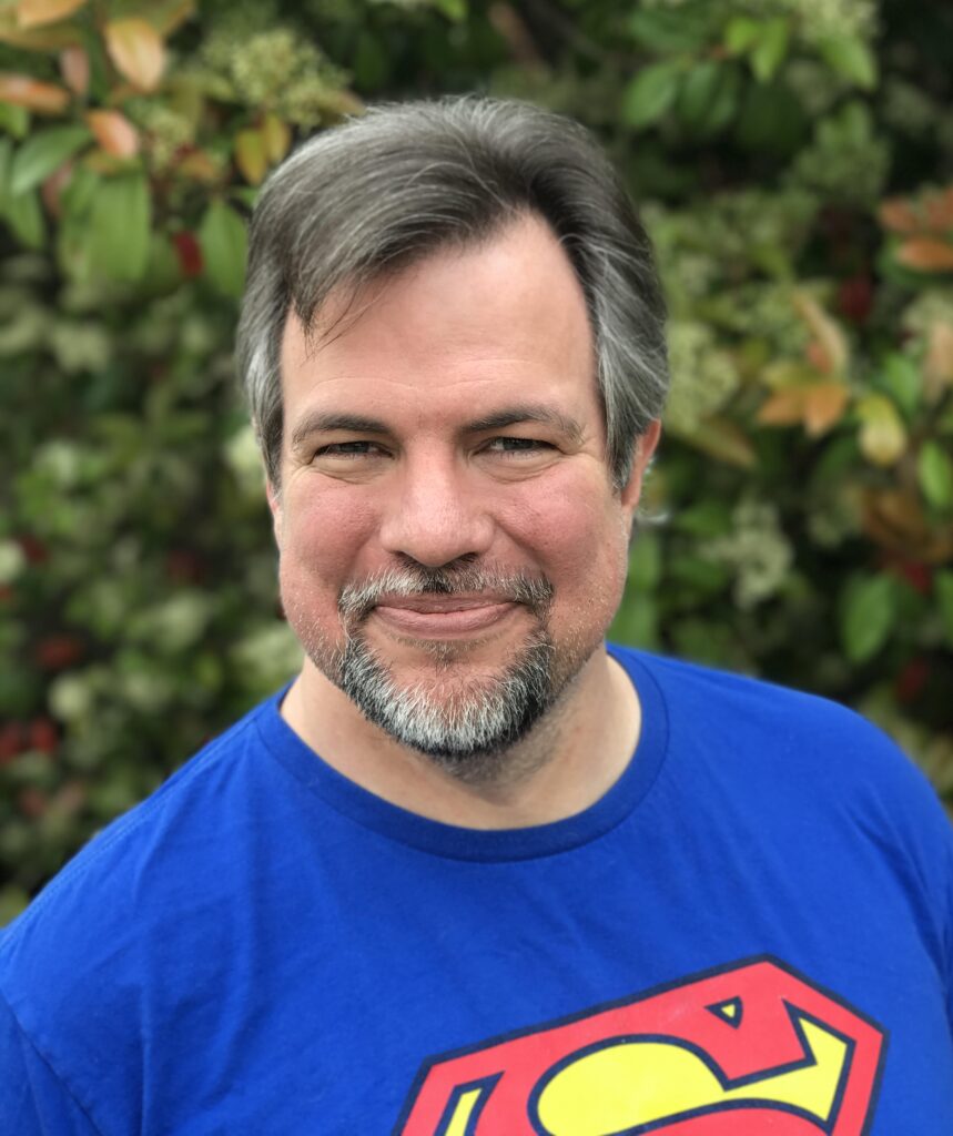 A Lee Martinez: author of 13 dark humor monster books, wearing a Super Man shirt. 